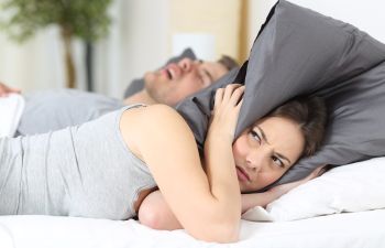 Woman with Piilow Over Head with Partner Snoring Atlanta GA