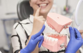 A woman patient pointing at her tooth and a dentist with a dental model explaining treatment options.
