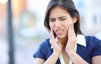 Woman with jaw pain and discomfort caused by TMJ disorder.
